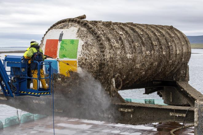 A large metal capsule is being cleaned of algae